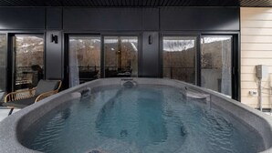 Ein Whirlpool mit Steinfassung, ein Sessel und eine Glastür zum Außenbereich.