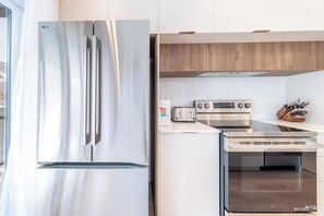 A modern kitchen with stainless steel appliances, including a refrigerator, oven, and toaster.