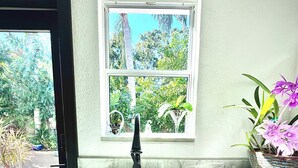 A kitchen with a sink, cabinets, and a window overlooking a garden. - Luxurious upscale guest suite with private entrance and private tropical garden. (Gulfport)
