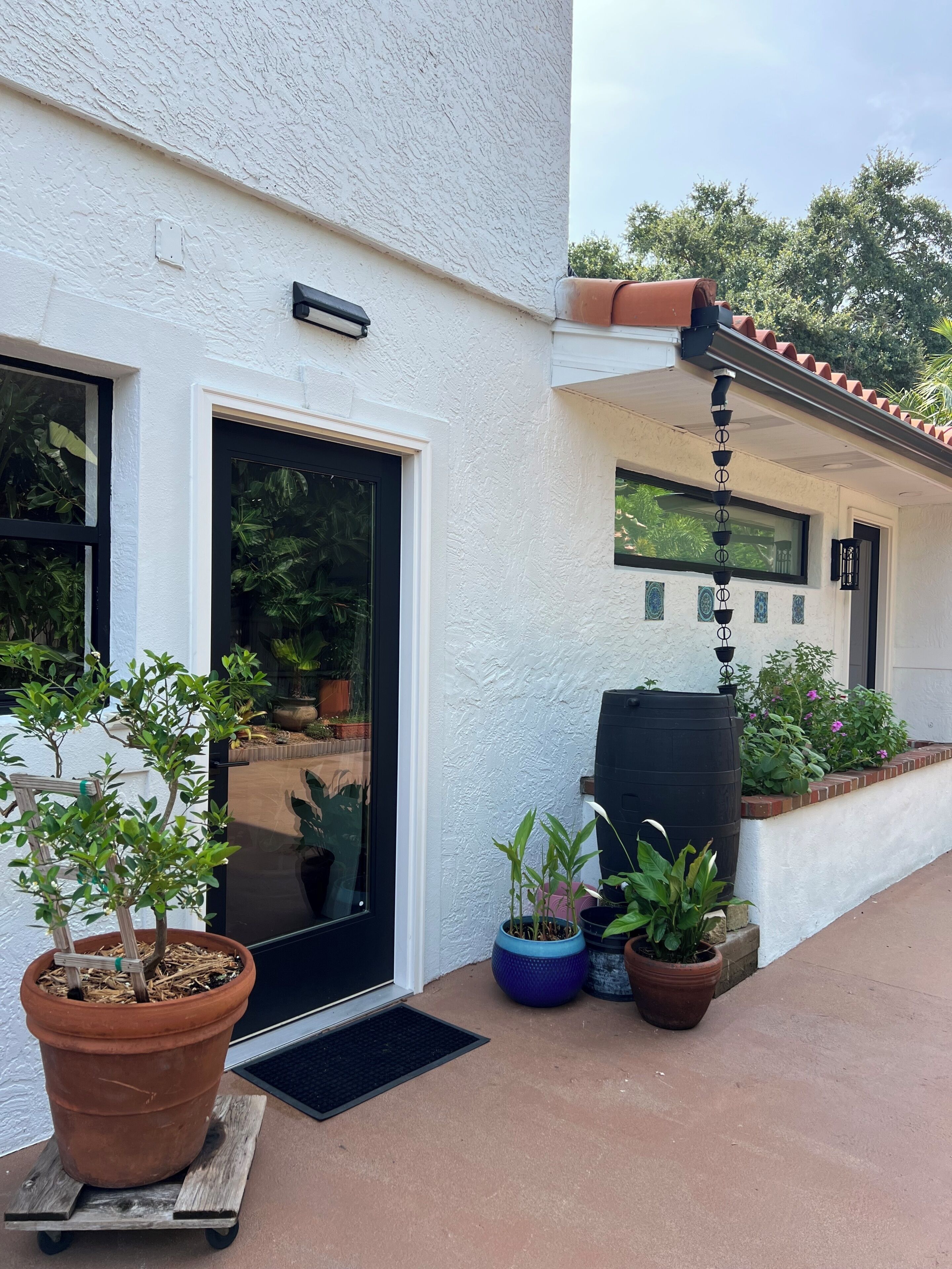 Ein Haus mit schwarzem Eingang, Pflanzgefäßen und einem kleinen Garten.