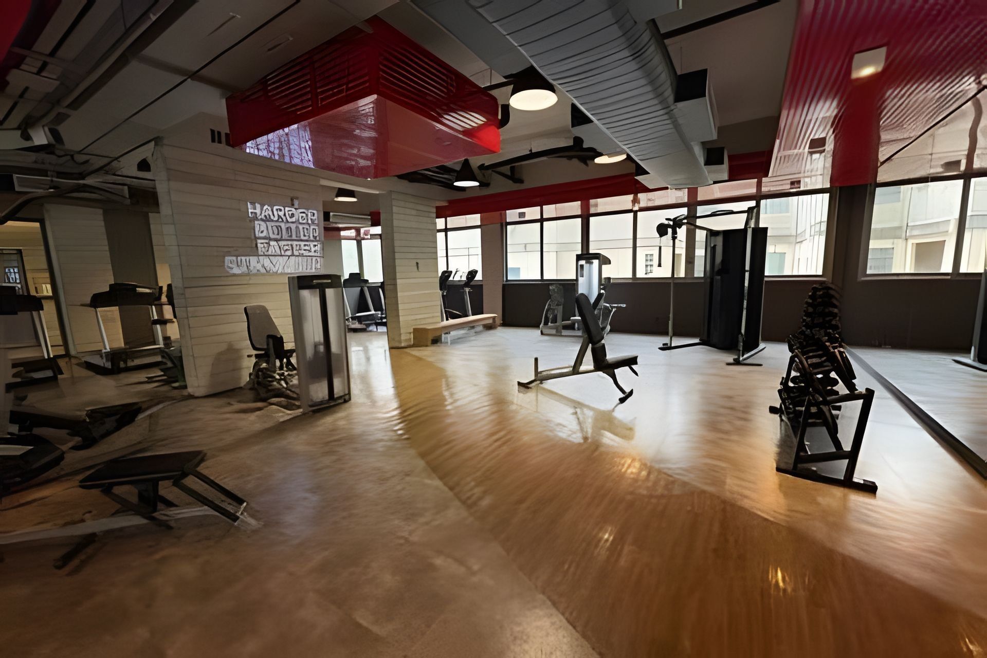 Une salle de sport équipée de matériel d’exercice, dotée de grandes fenêtres et arborant une décoration aux couleurs rouge et blanche.