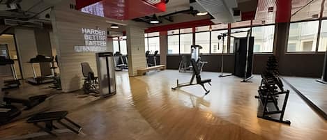 A gym with exercise equipment, large windows, and a red and white color scheme.