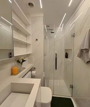 Ein modernes Badezimmer mit einer Duschkabine aus Glas, einem weißen Waschbecken und einem großen Spiegel.