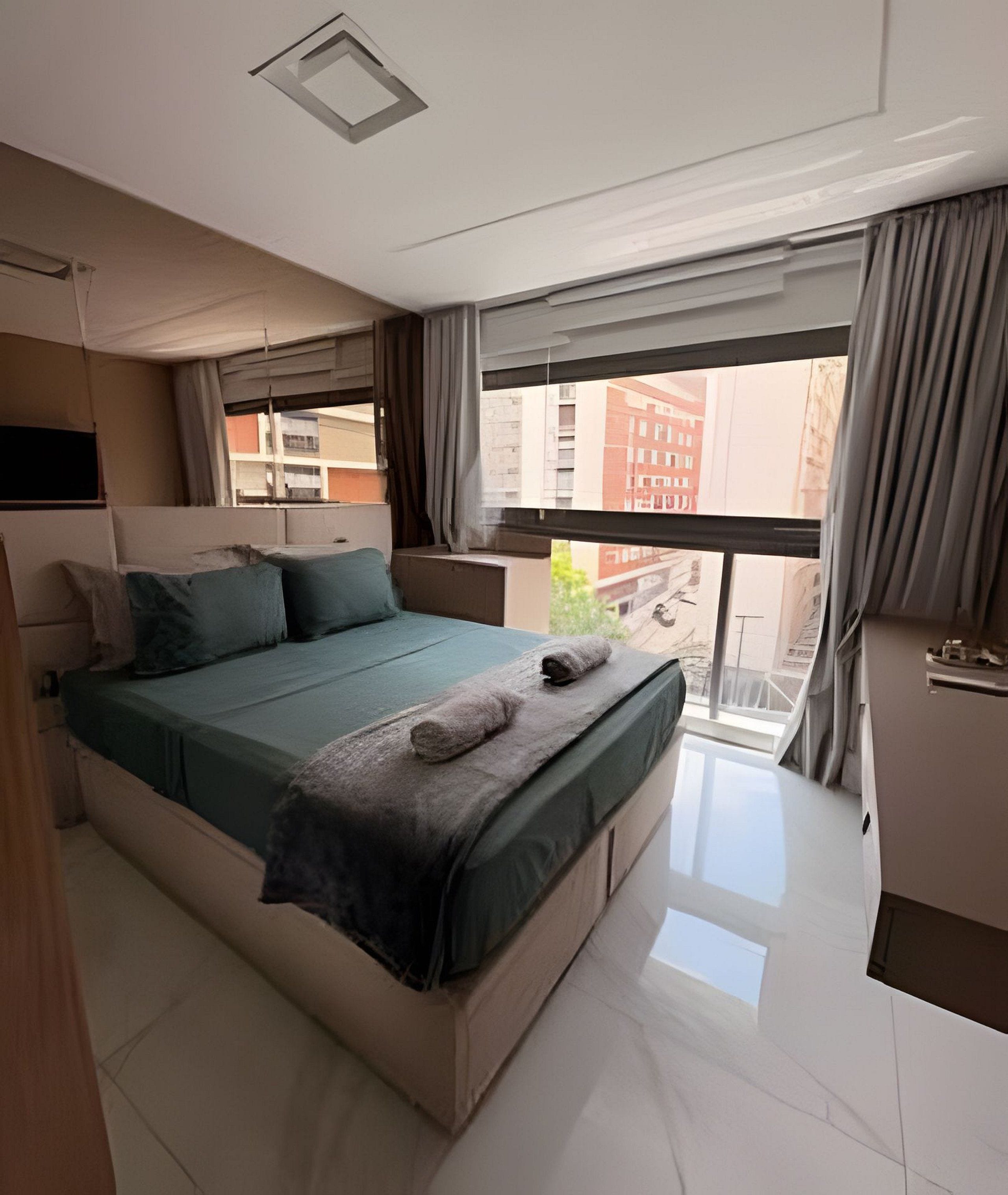 Een moderne slaapkamer met een groot bed, een inbouwkast en een balkon met uitzicht op de stad.