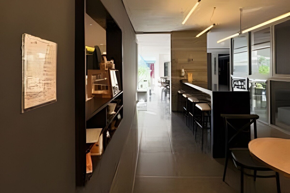 A modern interior with a long corridor leading to a dining area with tables and chairs.