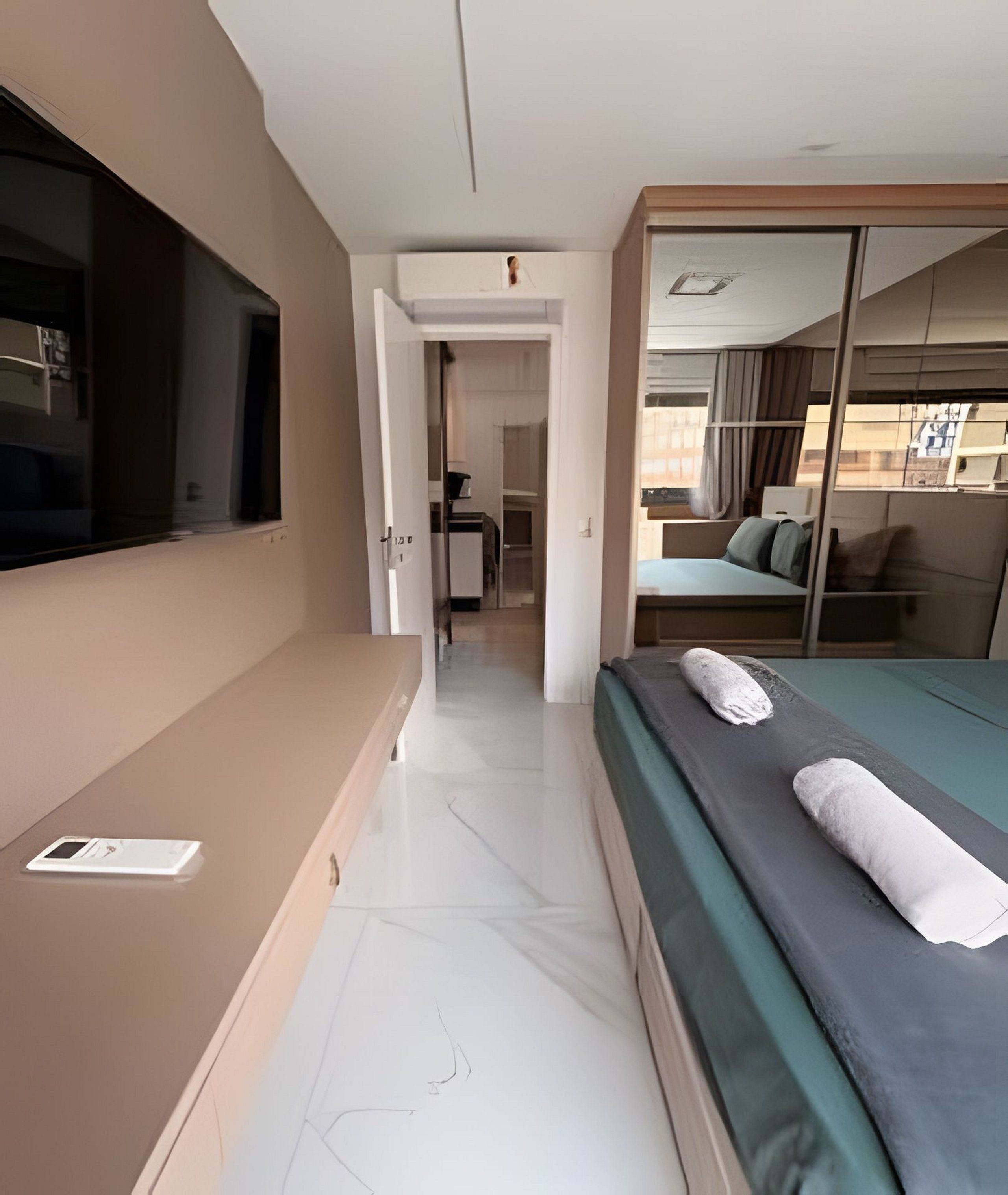 Una camera d'albergo con un letto, una televisione, una scrivania e una porta scorrevole che dà su un balcone.