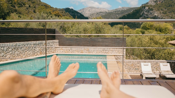 A poolside view with a mountain backdrop, including a pool, lounge chairs, and a stone wall. - La Villa de Ca'n Beneït (IB)