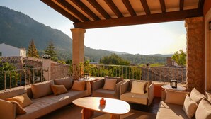 Un espacio de estar al aire libre con techo, que incluye un sofá y una mesa, con vistas a un paisaje montañoso.