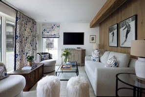 Ein modernes Wohnzimmer mit Sofa, Sesseln, Couchtisch und Fernseher.