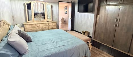 Un dormitorio con cama, cómoda, espejo, armario y una araña.