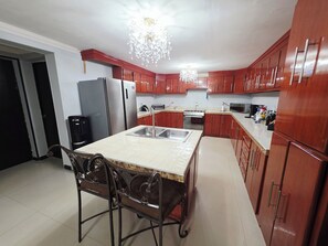 A kitchen with a central island, stainless steel appliances, and wooden cabinets. - Casa renovada,espaciosa y segura con lavadora y secadora. Facturamos (Heroica Ciudad de Cananea)