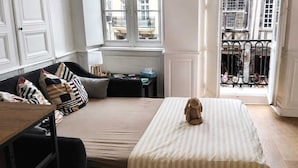Ein Zimmer mit einem Bett, einem Sofa, einem kleinen Tisch und einem Fenster mit Blick auf Gebäude.