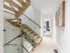 A modern staircase with glass railings and wooden steps. - Luxury 3BR Toronto Home | Little Italy & Bloor West | Parking (Toronto)