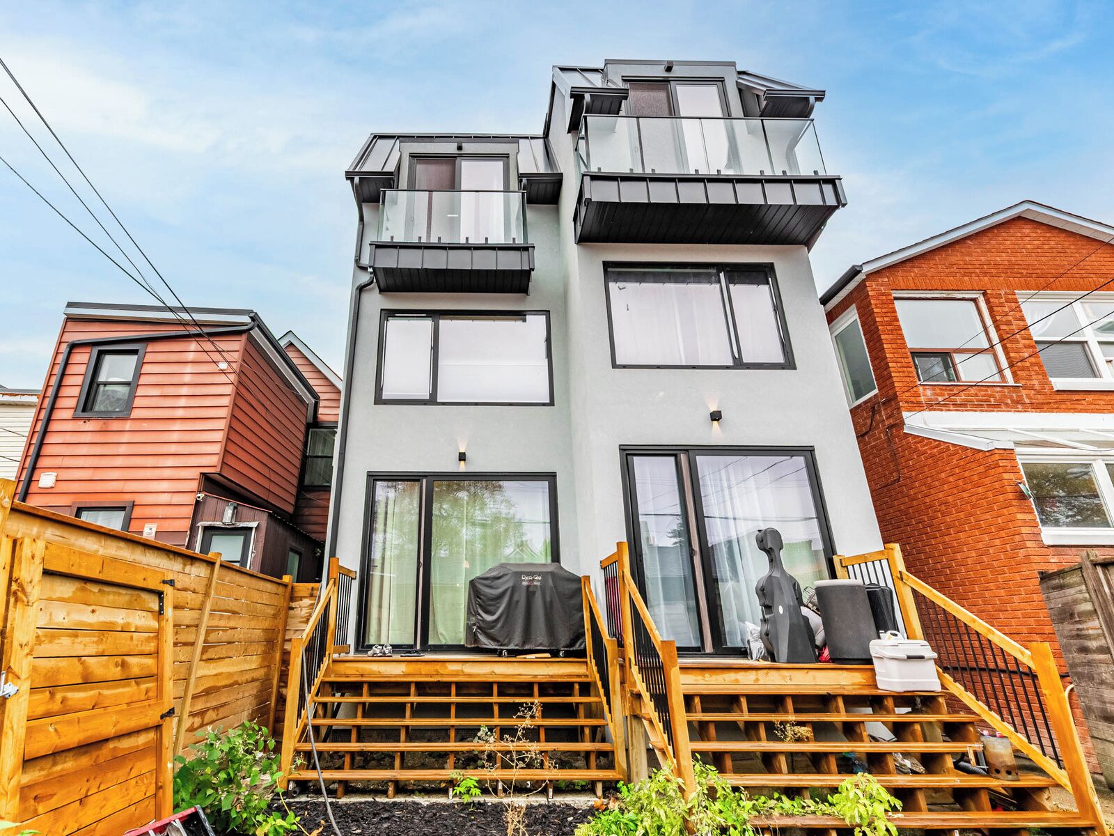 A modern two-story house with a balcony, a wooden deck, and a garage.