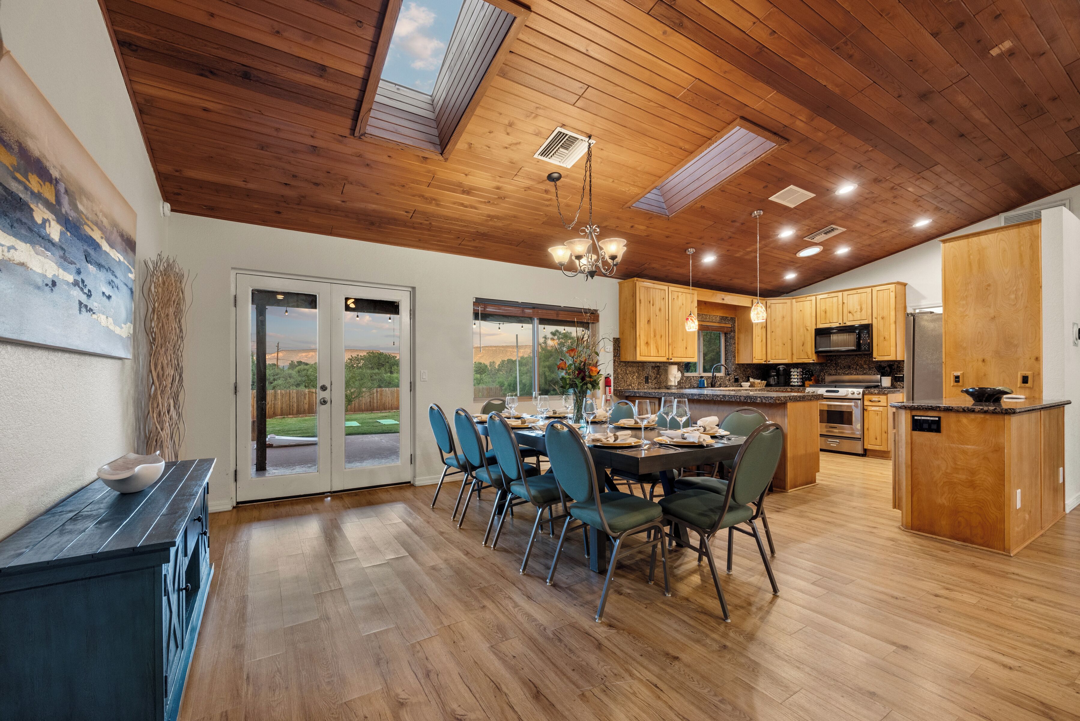 A modern kitchen with wooden cabinets, a central island, and a dining area with chairs.