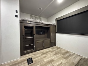 A room with a built-in entertainment center, a window, and a vent on the ceiling.