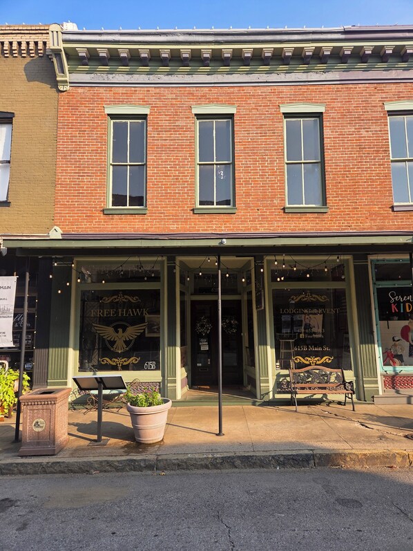A brick building with a green awning, a bench outside, and a sign that reads 'FREE HAWK'.