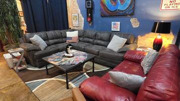 Un salon chaleureux avec un canapé d’angle, une table basse et un fauteuil en cuir rouge.