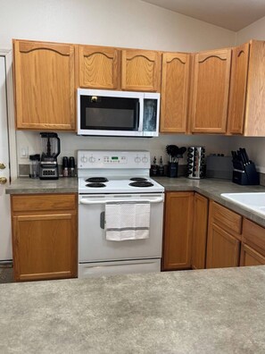 A kitchen with wooden cabinets, a white stove, a microwave, and a coffee maker.