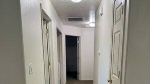 A hallway with carpeted floors, white walls, and doors leading to other rooms. - Quiet Home Near Everything (Hermiston)