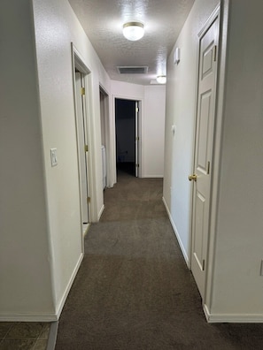 A hallway with carpeted floors, white walls, and doors leading to other rooms. - Quiet Home Near Everything (Hermiston)
