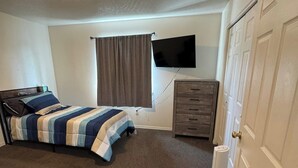 A bedroom with two beds, a television, a dresser, and a door. - Quiet Home Near Everything (Hermiston)