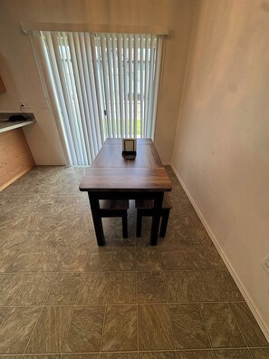 A room with a wooden table, a bench, and a window with blinds. - Quiet Home Near Everything (Hermiston)