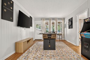 A room with a flat-screen TV mounted on the wall, a dartboard, and a dart machine.