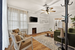 A living room with a fireplace, a television, and a ceiling fan.