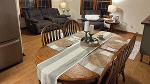 Un comedor con una mesa de madera, sillas y una araña.