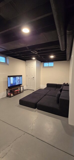 A basement with a sectional sofa, a television on a stand, and a door. - Marvelous 3-bedroom house in friendly Cleveland neighborhood (Cleveland)