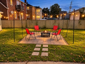 A patio with a fire pit, red chairs, and string lights. - Marvelous 3-bedroom house in friendly Cleveland neighborhood (Cleveland)