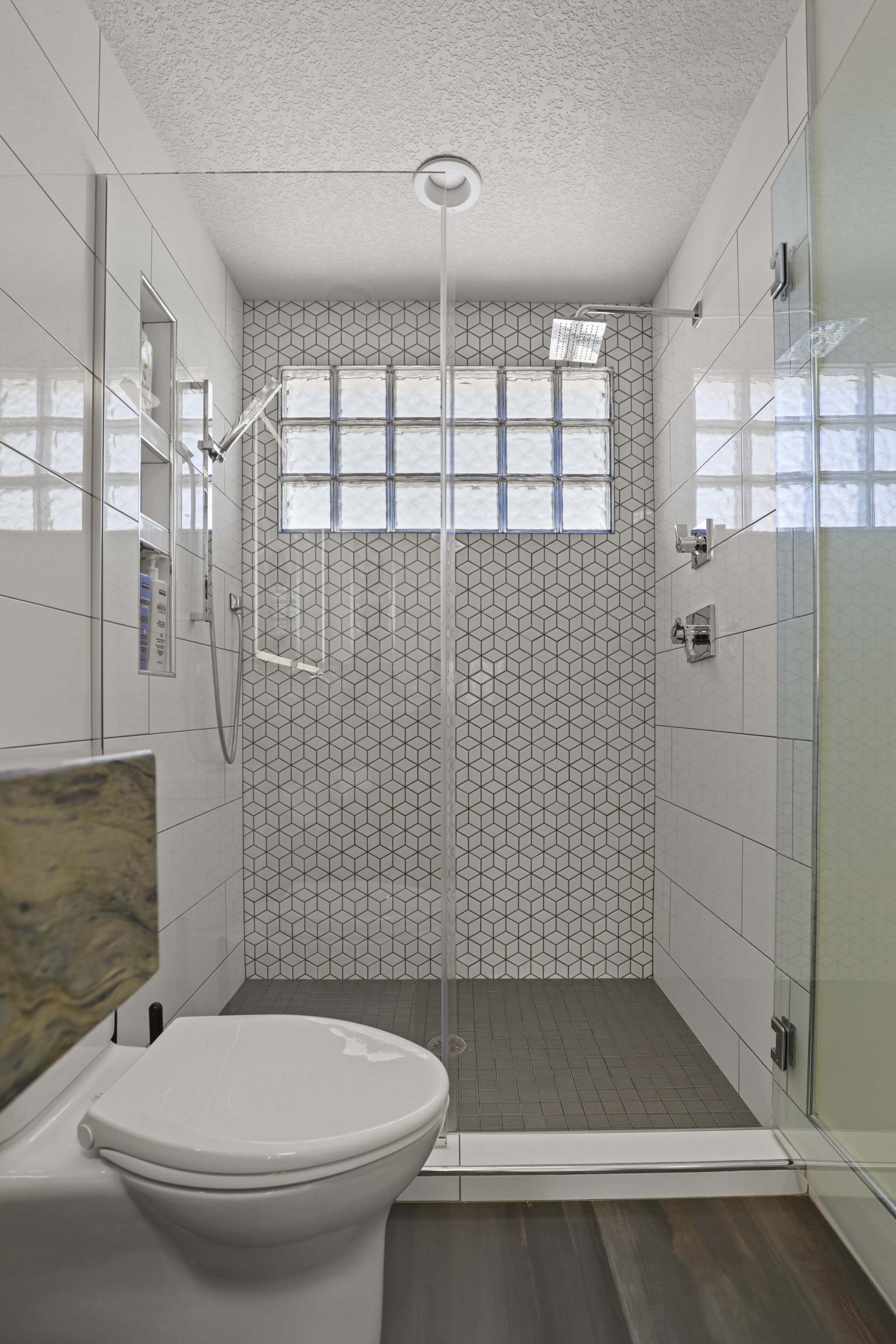 Une salle de bain moderne avec une douche à parois de verre, des toilettes et un meuble-lavabo avec un miroir.