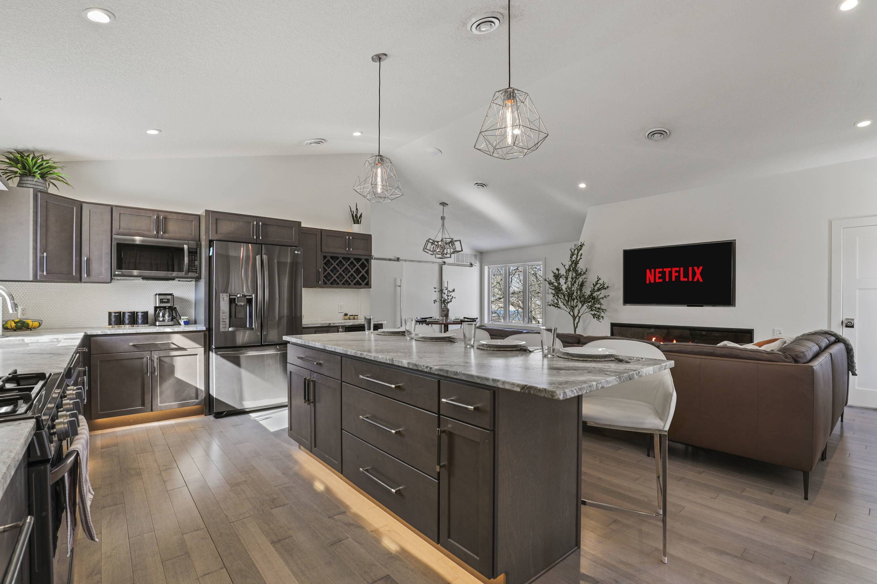A modern kitchen with stainless steel appliances, a central island, and pendant lighting.