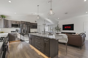 Una cocina moderna con electrodomésticos de acero inoxidable, una isla central e iluminación colgante.