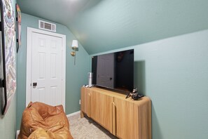 Een kamer met een grote flatscreen televisie bevestigd aan een houten kast, een witte deur en een bruine leren bank.