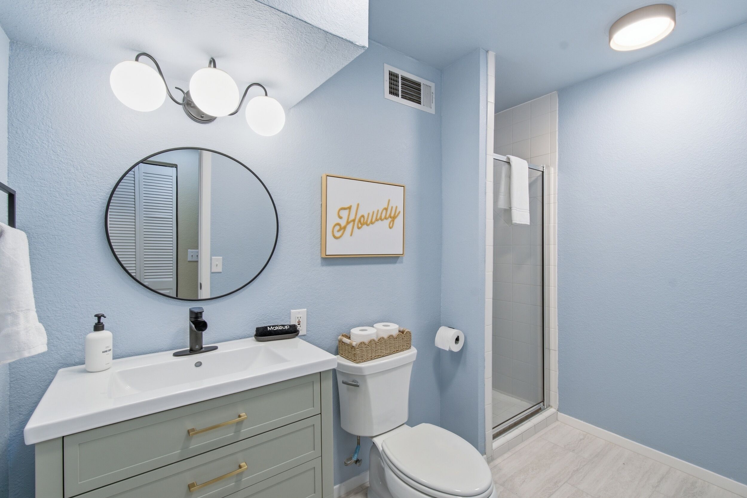 A bathroom with a sink, mirror, toilet, and shower.