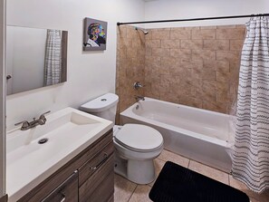 Een badkamer met een bad, toilet en wastafel.