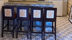 Una cocina con techo de madera, armarios blancos, salpicadero de azulejos y una zona de bar con sillas.