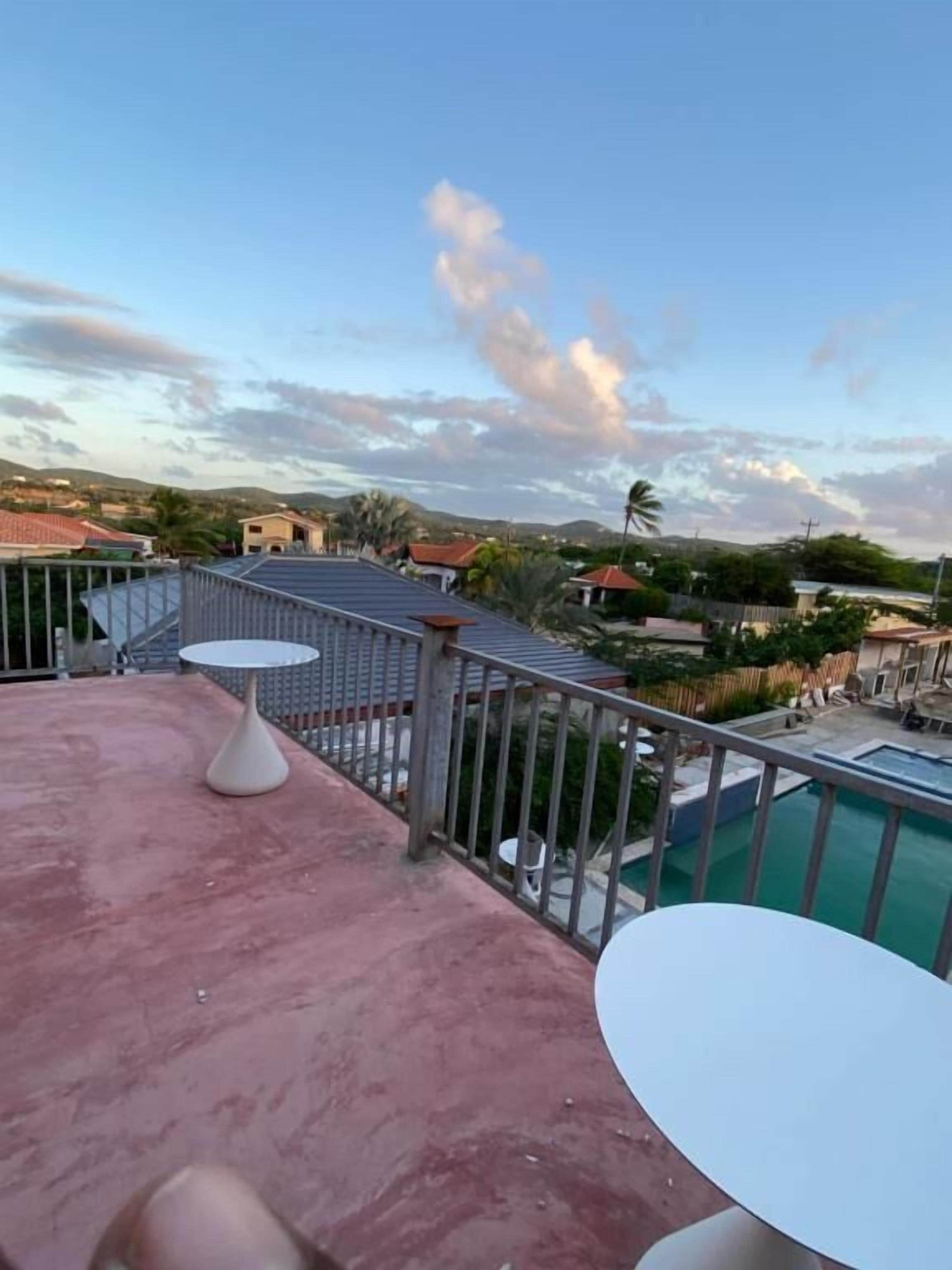 Une terrasse sur le toit avec une piscine, des tables et une vue sur le paysage environnant.