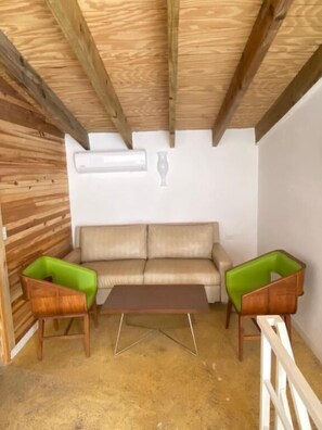 A room with a wooden ceiling, a beige sofa, two green armchairs, and a wooden coffee table. - Arco Iris Casa de Campo  (Santa Cruz)