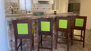 Une cuisine avec un plafond en bois, un sol carrelé et un coin bar avec des chaises.