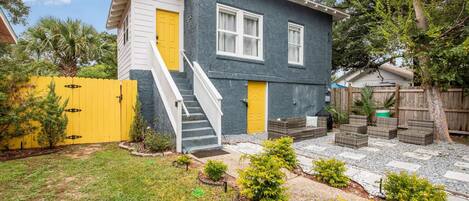 Ein zweistöckiges Haus mit Vordergarten, einem gelben Tor und einer Treppe, die zum Eingang führt.