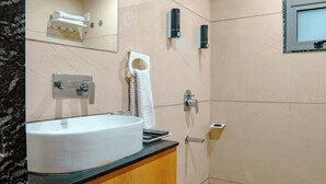 Baño con lavamanos, espejo, toallero y zona de ducha.