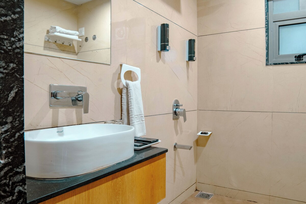 A bathroom with a sink, mirror, towel rack, and shower area.