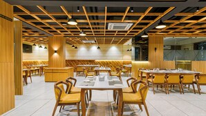 Un restaurante con paneles de madera, varias mesas de comedor y sillas amarillas.