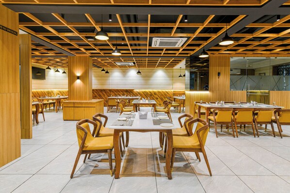 A restaurant with wooden paneling, multiple dining tables, and yellow chairs.