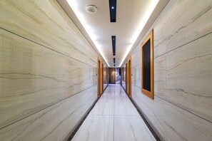 A corridor with marble walls and a tiled floor, leading to a staircase. - Aceotel Premier Astoria Indore (Indore)