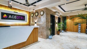 Zona de recepción de un hotel, con mostrador de recepción, relojes y el letrero de recepción.