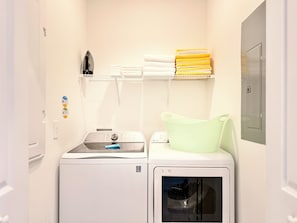 A laundry room with a washing machine, dryer, and stacked towels on a shelf. - 5-bedroom townhome with Club Access, PVT Pool, BBQ Grill just 15 min from Disney (Kissimmee)